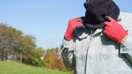 ネックウォーマーで防寒対策をする作業服の男性