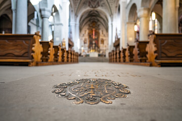 Metal inscription and ornaments on the bottom of the brightly lit Romanesque three-nave columned...