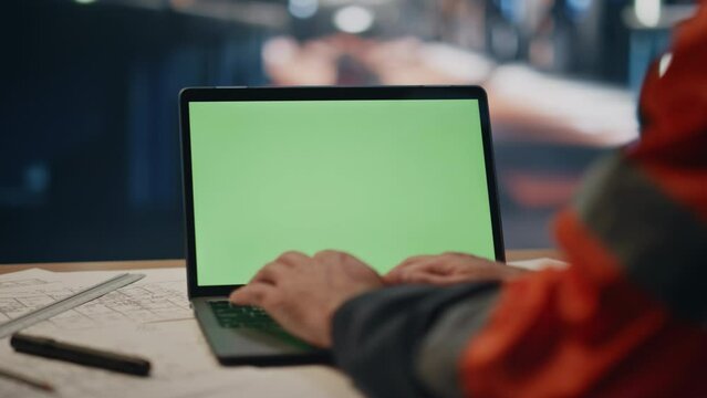 Factory worker typing green screen laptop on plant workshop close up. Engineer
