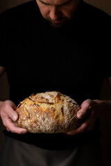 Attractive young Caucasian chef posing with white sourdough bread. The sourdough bread is the...