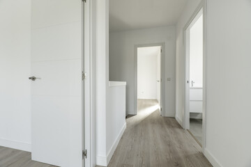 Fototapeta na wymiar Distributor hallway of a two-story single-family residential home with white wood carpentry on doors and moldings and light-colored flooring on the floor
