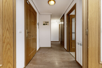 Distributor hallway of a residential home with oak carpentry on doors and moldings and light-colored flooring on the floor