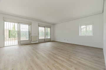 Living room of an empty house with white painted walls, large exit doors to the plot with security doors and wooden floors