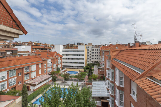 Panoramic image of an open block patio between facades and roofs of urban residential buildings and a playground with swimming pools