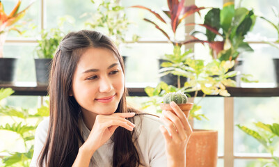 Portrait garden beautiful pretty young Asian woman wearing white blouse with long black hair and smile fresh happy relax bright smile look hand holding pot small tree leafgreen plant in room shop - obrazy, fototapety, plakaty