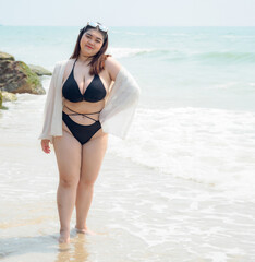 Portrait young woman asian chubby fat cute beautiful one person in bikini black sexy frontview tropical sea beach white sand clean and blue sky background calm nature ocean wave water travel fun happy - obrazy, fototapety, plakaty