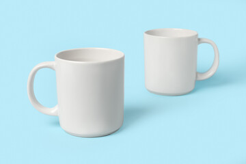 Two white ceramic mugs on light blue background