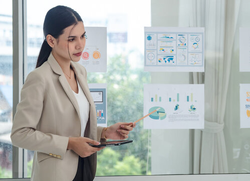 Portrait business woman one oerson handsome smart Asian stand holding pen and looking creative write note plan maketing idea project ready happy working online sale inside home office with intention