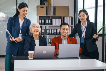 Four asian people in an office, working together on laptops, discussing tasks. annual gathering where attendees share and discuss opinions, presentation teamwork group meeting laptop in boardroom