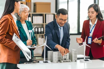 Fotobehang Four asian businesspeople professionals discuss renewable energy in office, showing solar panel and wind turbines with tower building model, apartment. modern business with environmental, clean energy © makibestphoto