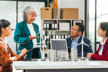 Four asian businesspeople professionals discuss renewable energy in office, showing solar panel and...