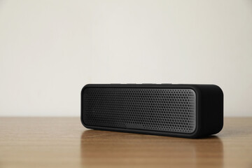 One black portable bluetooth speaker on wooden table. Audio equipment