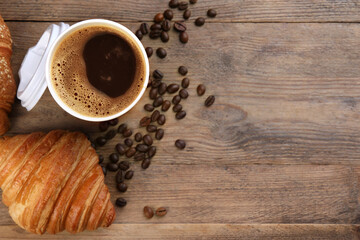 Coffee to go. Paper cup of tasty drink, croissants and beans on wooden table, flat lay with space for text