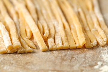 Fototapeta na wymiar Raw homemade pasta and flour on wooden table, closeup