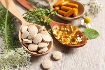 Fototapeta na wymiar Different pills, herbs and flowers on wooden table, closeup. Dietary supplements