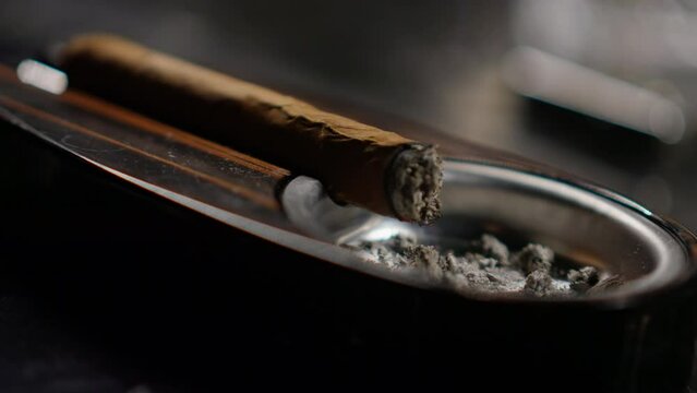 A cigar is placed in an expensive ashtray. Close up shot