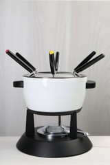Fondue set on white wooden table. Kitchen equipment