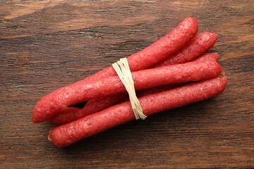 Many thin dry smoked sausages on wooden table, top view