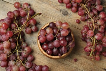 Delicious fresh red grapes on wooden table, flat lay