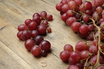 Delicious fresh red grapes on wooden table, closeup