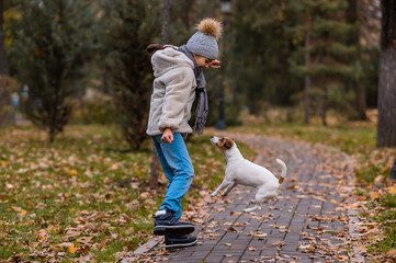 Fototapeta premium Caucasian girl playing with a dog for a walk in the autumn park. 