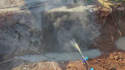 Aerial view of workers working on the shotcrete process, where the process is by firing concrete or spraying concrete into the ground covered by a wire mesh. Commonly used for retaining walls.