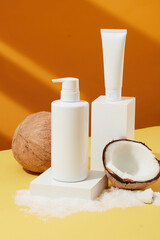 Unlabeled cosmetic tubes and bottles, fresh coconuts and coconut chips decorated around, with a yellow background. Cosmetics extracted from coconut, vegan, not tested on animals and good for the skin.