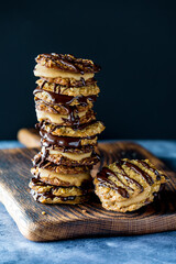 A tall stack of chocolate caramel lace cookies, against a dark background.