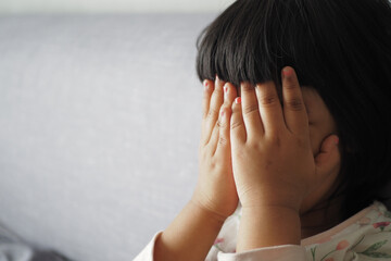 a upset child girl cover her face with hand 