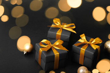 Obraz na płótnie Canvas Black gift box with golden ribbon bow on black background