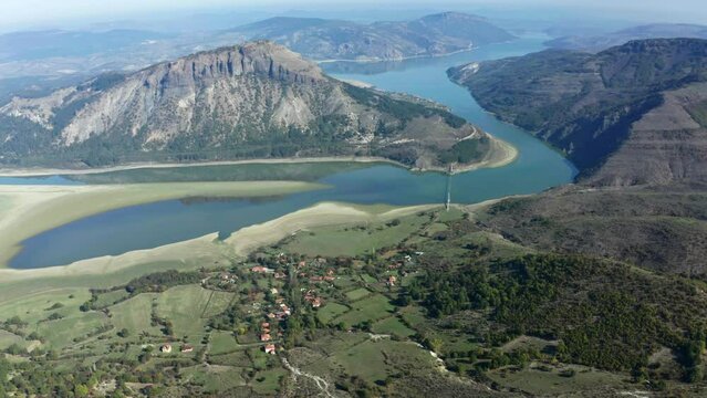 An aerial view of a mountain range with a river running between it, surrounded by a village in Bulgaria