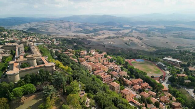 Aerial view of Historic Volterra town with old houses, towers and churches, Tuscany, Italy. Cinematic Aerial of Ancient Volterra village residential homes trees seen from above in medieval Tuscan town