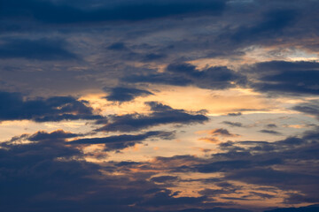 Sunset sky with golden rays of the sun against the background of silhouettes of mountain landscapes and rural villages. Aerial view of beautiful sky with clouds and sunlight during sunset.