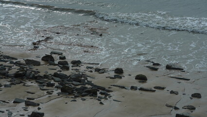 The ocean beach view with the rock shore and tide waves