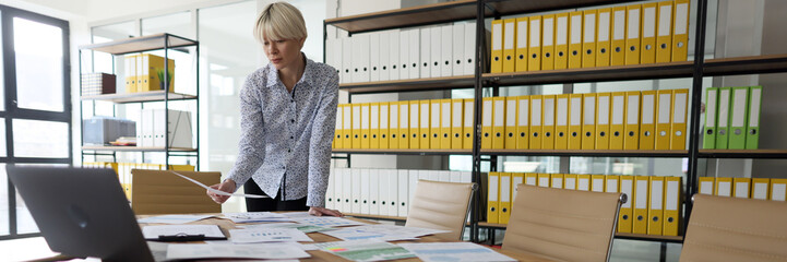 Businesswoman looks at papers in empty company office