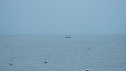 Obraz premium The peaceful sea view with the fishing boat sailing on it in the cloudy day