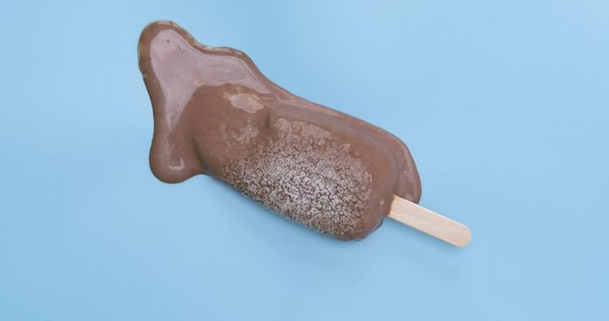 4K footage Time-lapse Top view Frozen popsicles melting with heat on blue background.