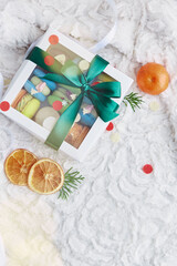 Aesthetic Christmas box of macaroons among tangerines. Sweet holidays present. New Year, Christmas gift background