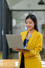 Asian business woman working happily Smiling woman raising her hands with a happy expression and looking at her laptop. Delighted to receive email announcing her annual bonus. concept of success.