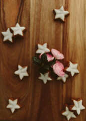 Gingerbread cookies in the shape of stars and pink roses on a wooden table. Christmas background. Winter card. Delicious pastries