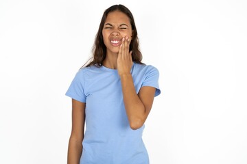 Beautiful girl wearing blue T-shirt touching mouth with hand with painful expression because of toothache or dental illness on teeth.