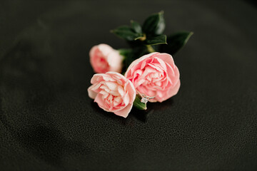Delicate pink roses and diamond engagement ring on a black background close up. Pink carnations. Beautiful flowers, a gift for February 14, Valentine's Day, Mother's Day. Place for text. Mock up.