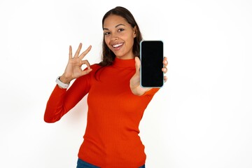 Beautiful girl wearing red sweater holding in hands cell showing ok-sign