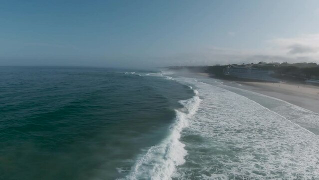 Aerial view of waves breaking during the world bodyboard competition on a sunny day at Praia Grande in Sintra.