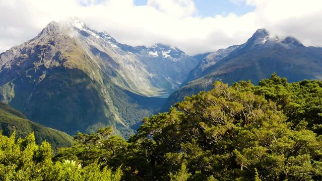 dramatic pan of hanging valley between mountains in New Zealand with windy bushes