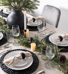Festive New Year's Eve dinner table adorned with a pine garland centerpiece, decorative woven black...