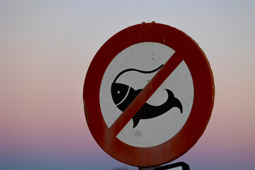 Señal de "prohibición de pesca" (prohido pescar) al atardecer