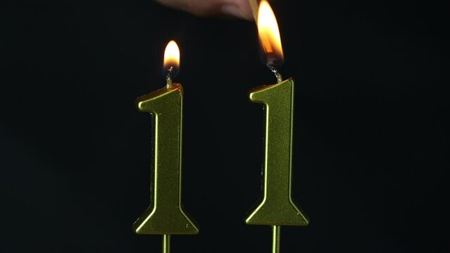 close up on the gold number eleven candle on a dark background.

