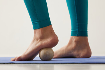 girl massaging her feet on a hard ball close-up on a white background, self-massage