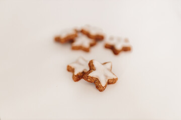 Gingerbread cookies in the shape of stars on a white table against a background of bokeh of New Year's golden lights. Christmas background. Winter card. Delicious pastries close-up